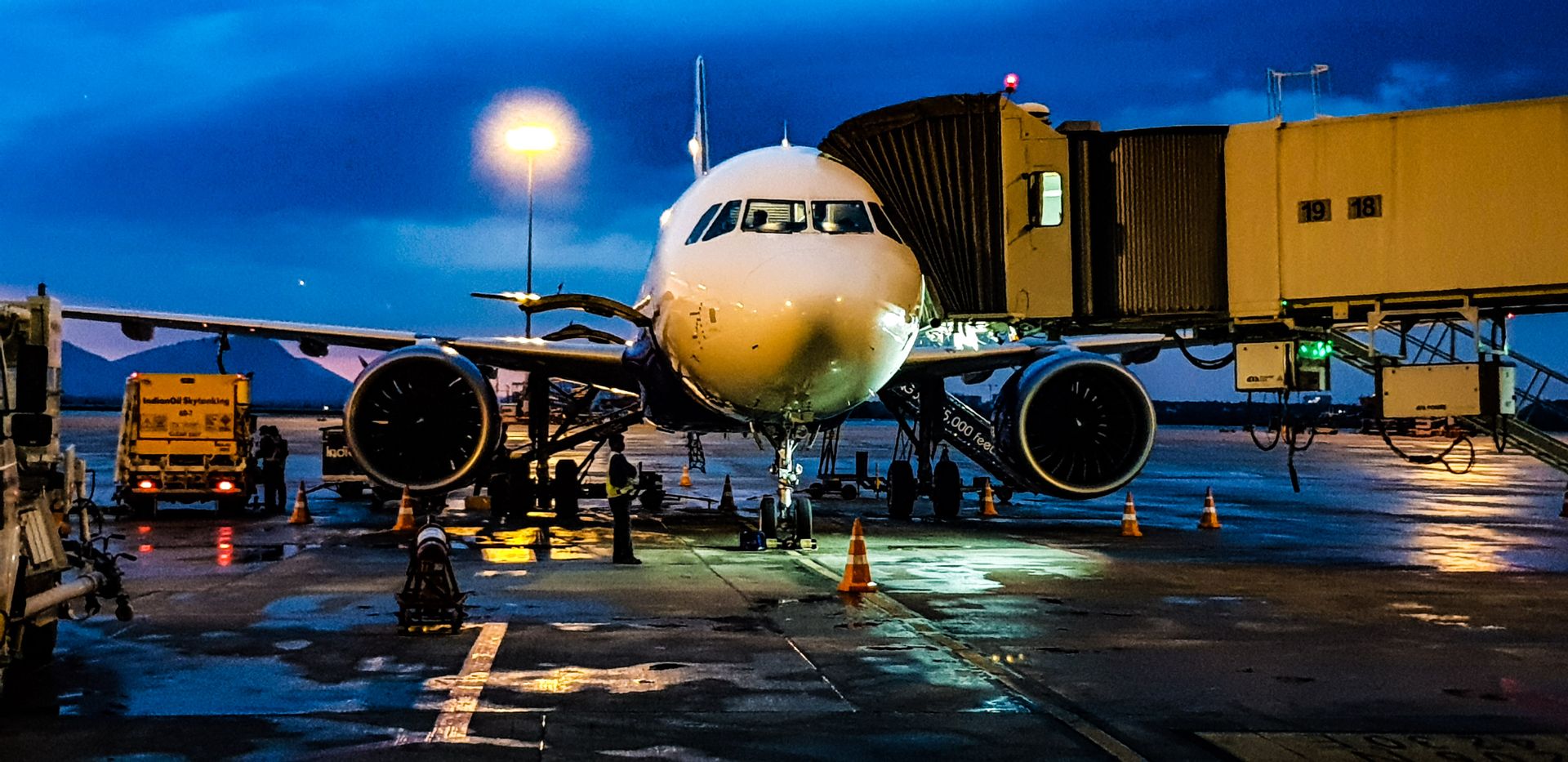 Aircraft at the gate at dusk with loaders and service trucks on the apron