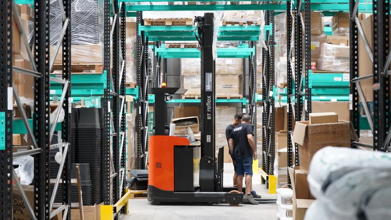 Warehouse team and forklift working between racking